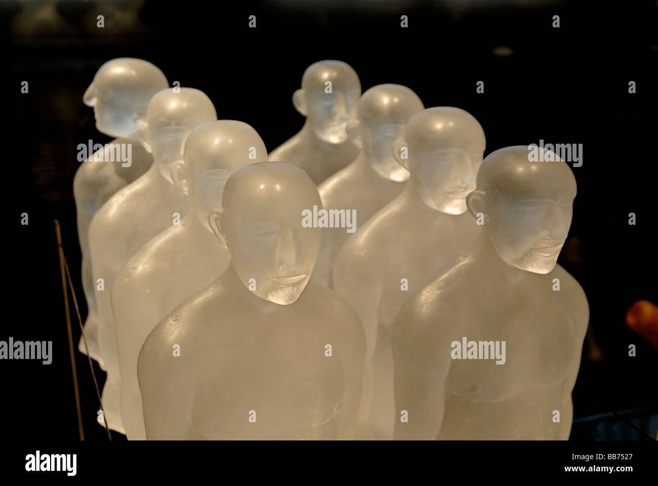 Two lines of glass figures with one head looking in a different direction Stock Photo