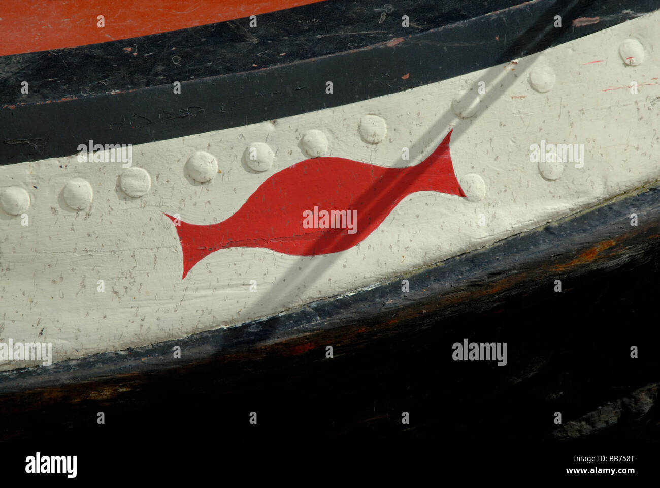 Red double curved lozenge shape decoration painted on rivetted bow of old working narrowboat, London, England Stock Photo