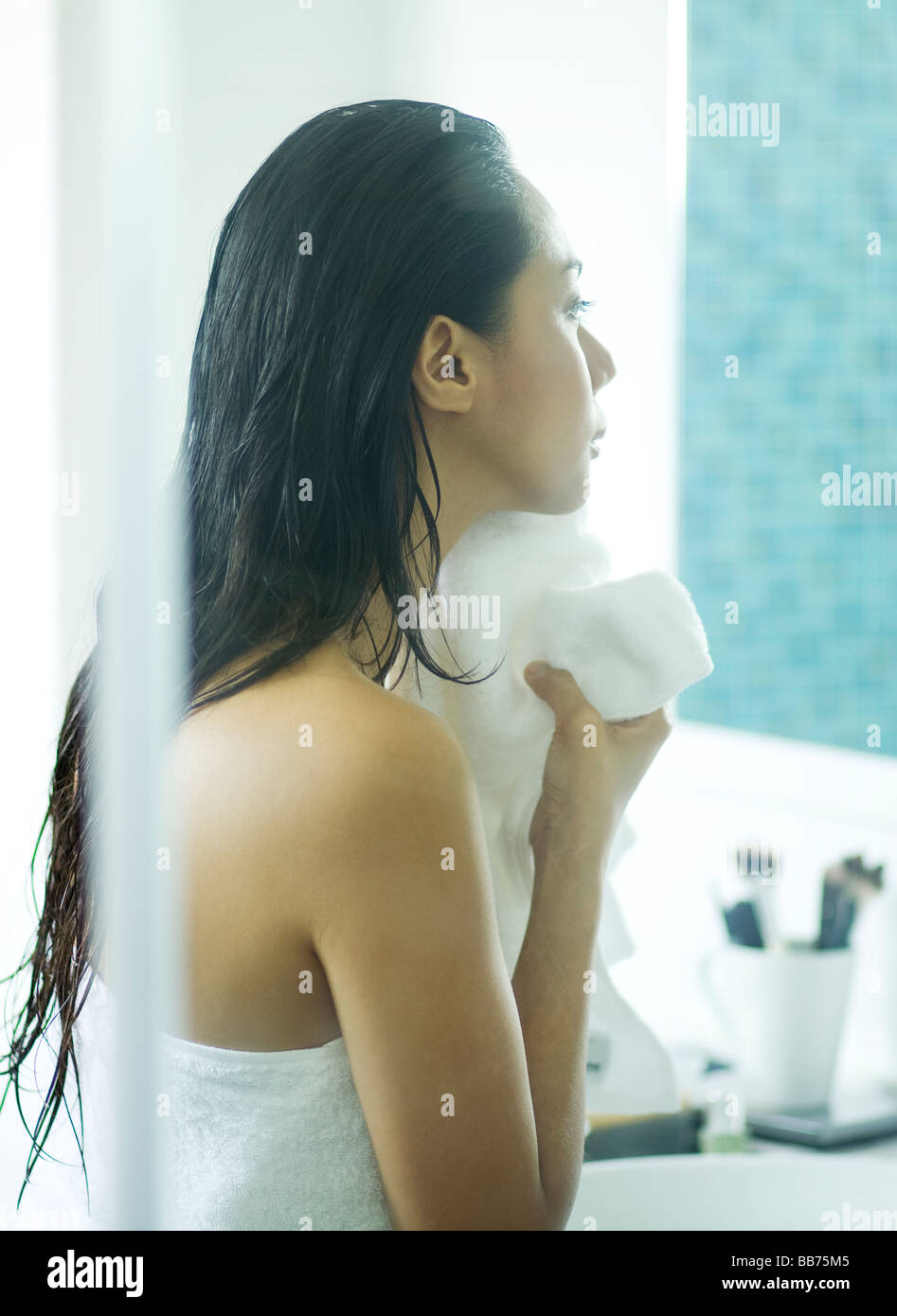 Woman wiping face with towel in bathroom Stock Photo