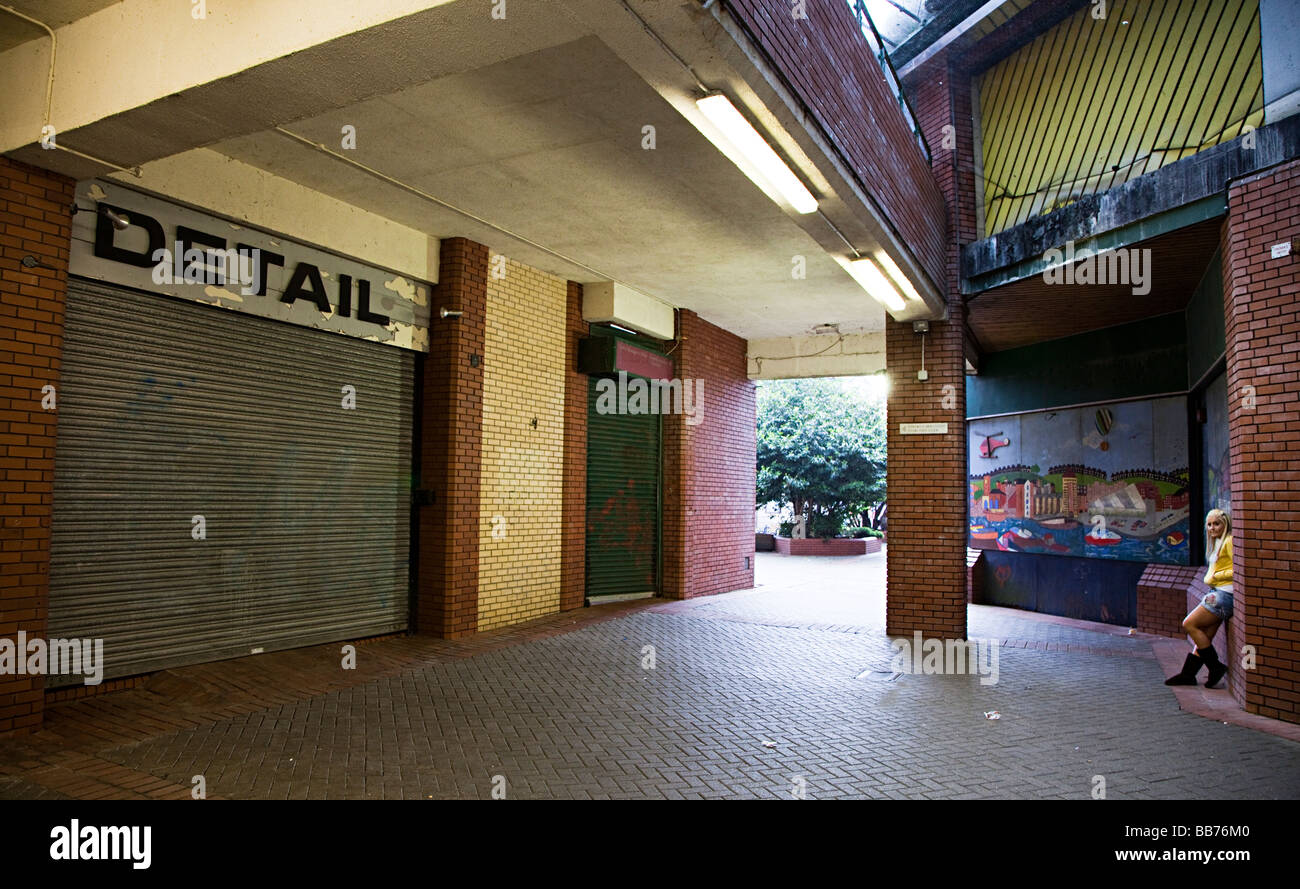 Girl in modern shopping complex with closed shops and shuttered windows Swansea Wales UK Stock Photo