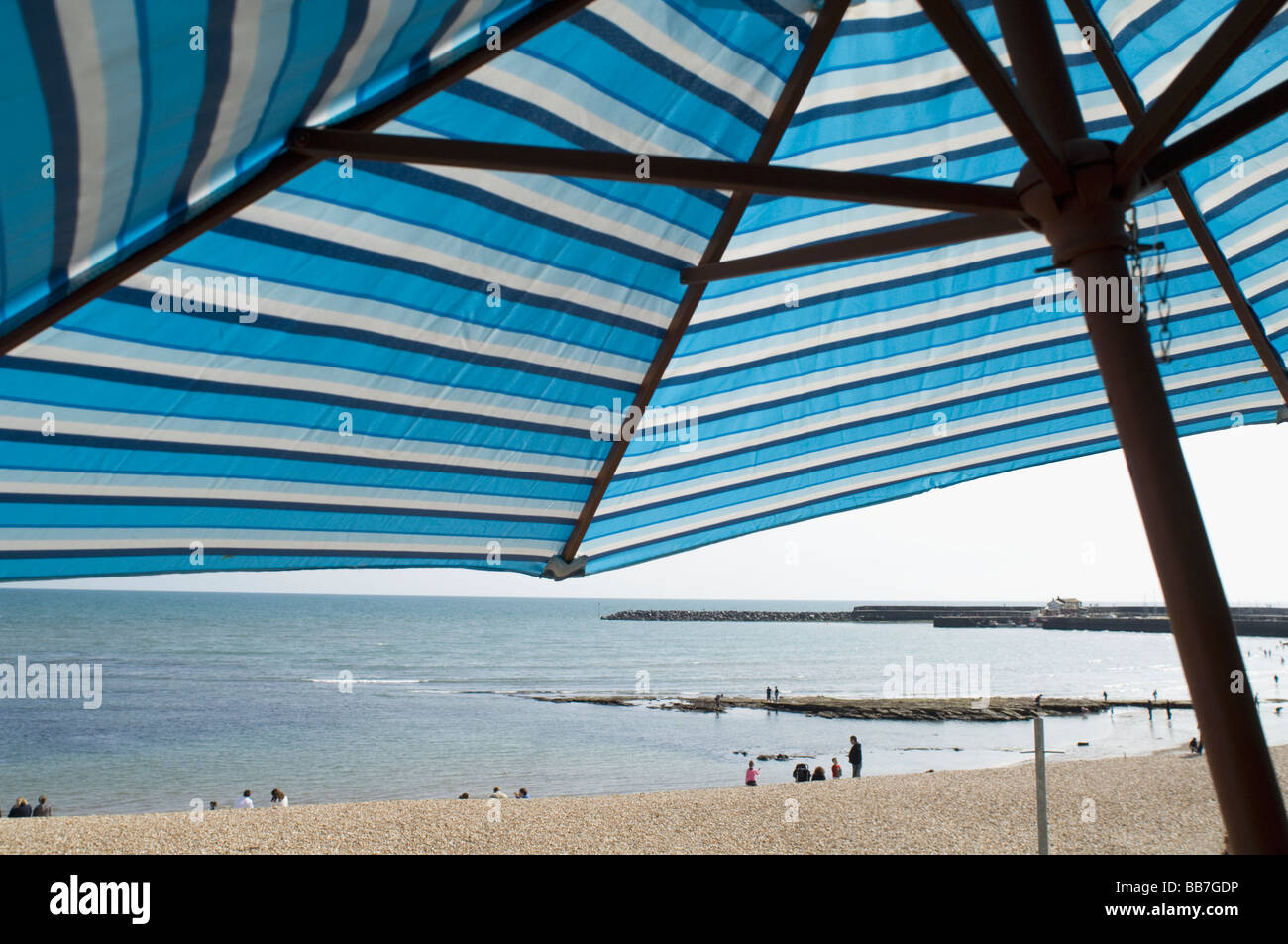 Large blue and white sun shade with Lyme Regis beach and cobb in back ground Stock Photo