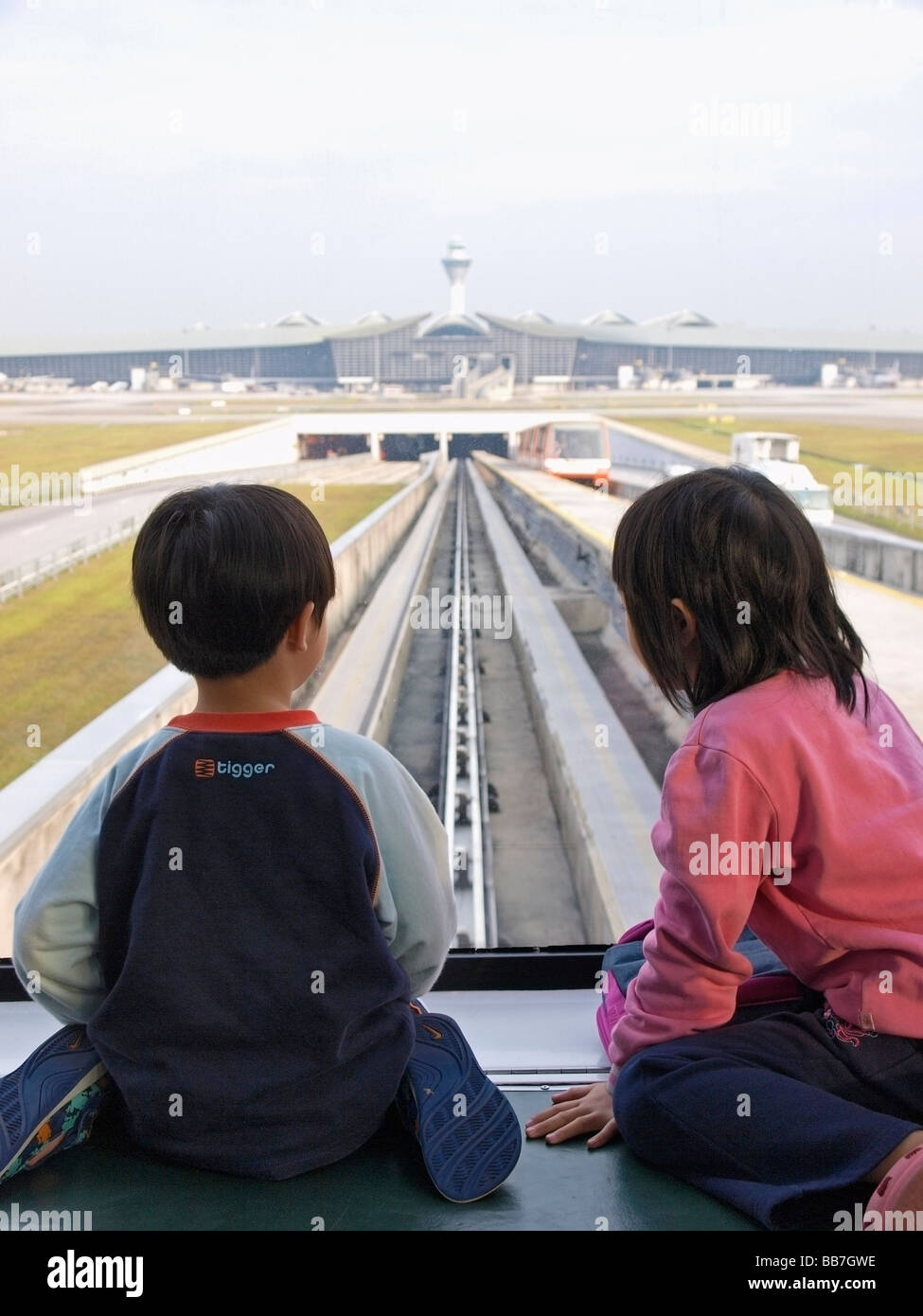 TWO YOUNG CHILDREN LOOKING BACK AT TRAIN ON TRANSFER TO DEPARTURE AREA,  KLIA AIRPORT SEPANG MALAYSIA Stock Photo