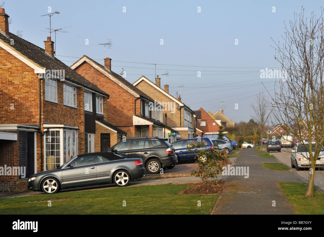 Residential turning street scene with householders cars parked in driveway front gardens of semi detached houses Stock Photo