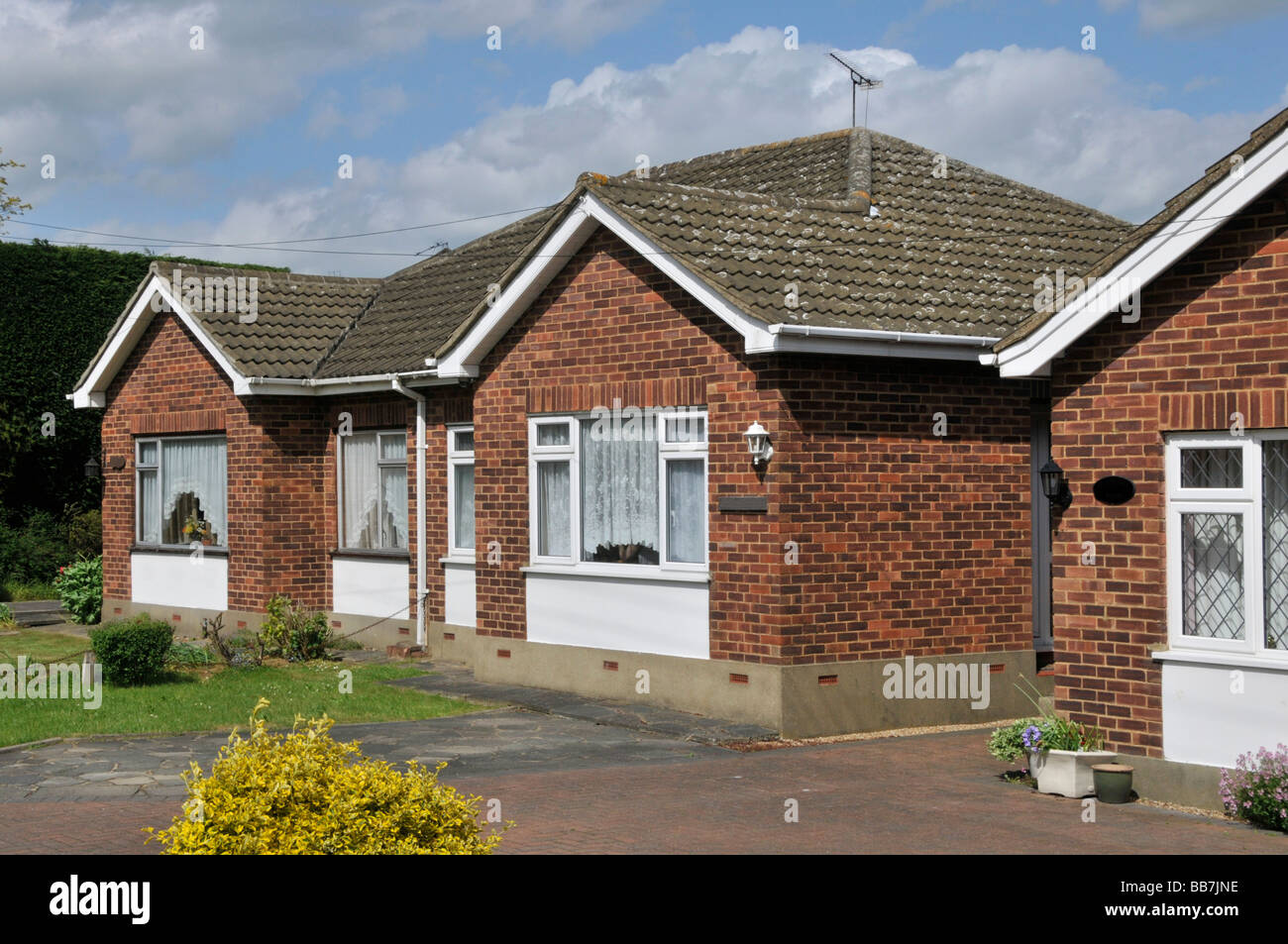 Semi detached brick built matching pair bungalow homes concrete tiled roof front gardens in rural village location near Brentwood Essex England UK Stock Photo