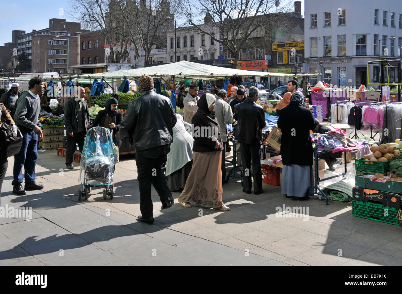 Shoppers on pavement around stalls in busy crowded Whitechapel outdoor street market in East London Borough of Tower Hamlets England UK Stock Photo