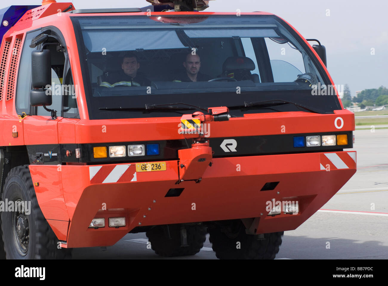 A Bright Red Fire Truck Speeding Along the Apron Road at Geneva Airport Switzerland Geneve Suisse Stock Photo