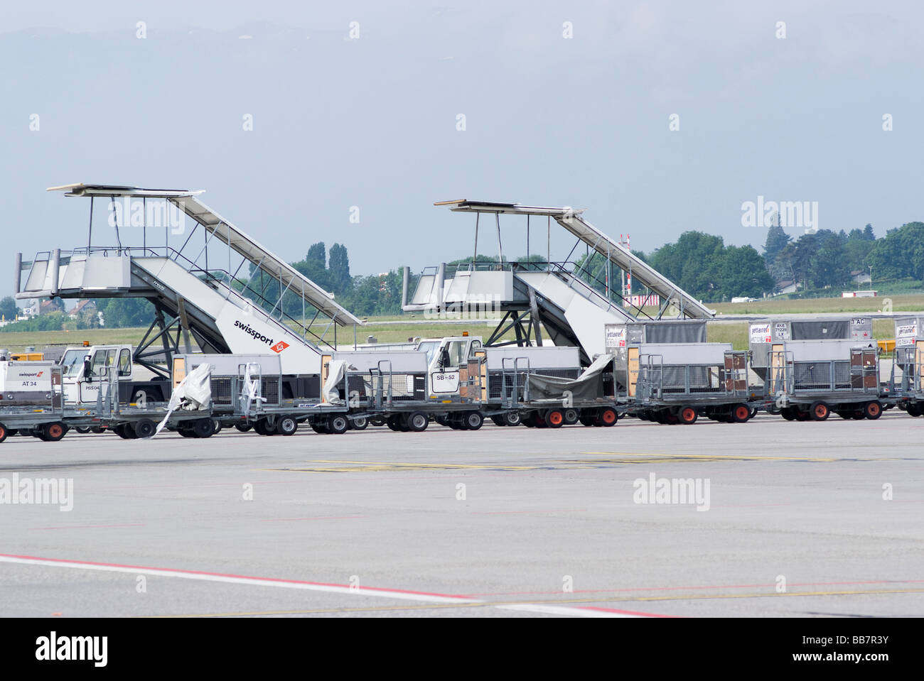 Airliner Stairways Baggage Carts and Tugs Parked in the Apron Area at Geneva Airport Switzerland Geneve Suisse Stock Photo