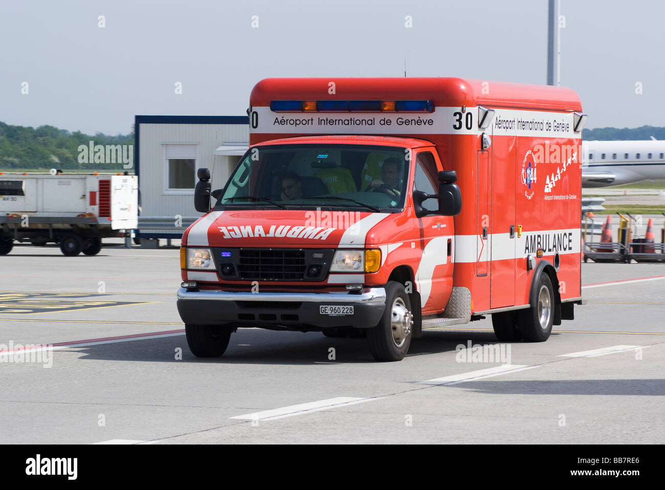 A Red Emergency Ambulance Speeds Along the Apron Road at Geneva Airport Switzerland Geneve Suisse Stock Photo