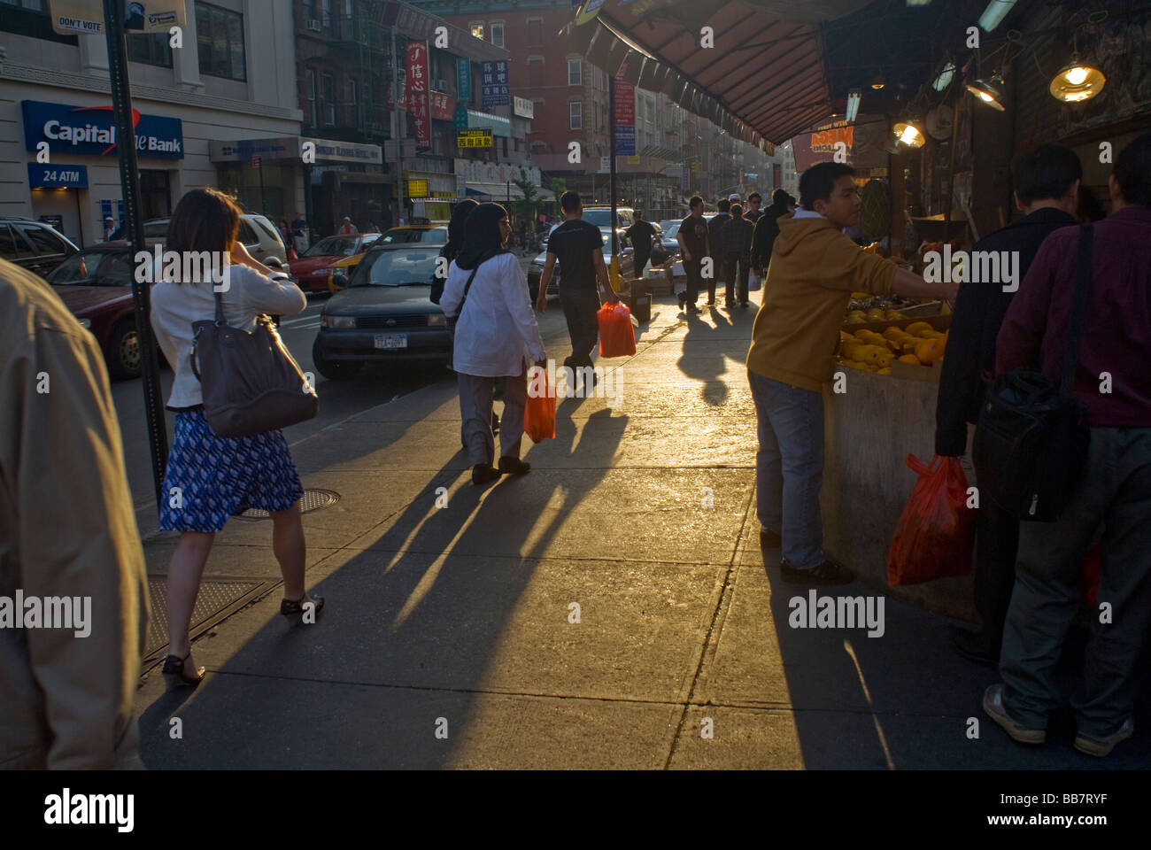 Shoppers in Chinatown in New York hurry home with plastic shopping bags filled with their purchases Stock Photo