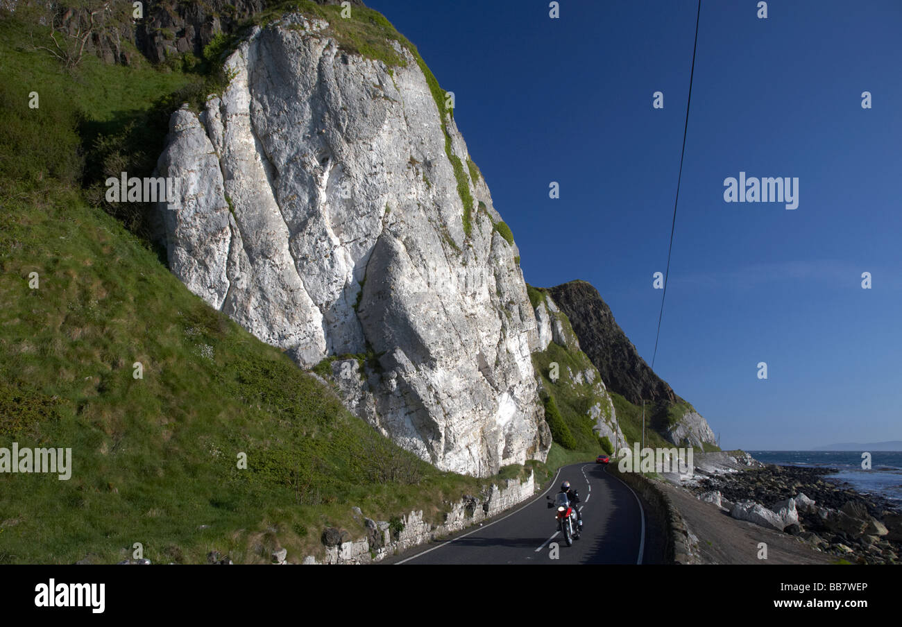 touring motorbike on the A2 causeway coastal route coast road at Garron Point under Limestone and basalt cliffs County Antrim Stock Photo