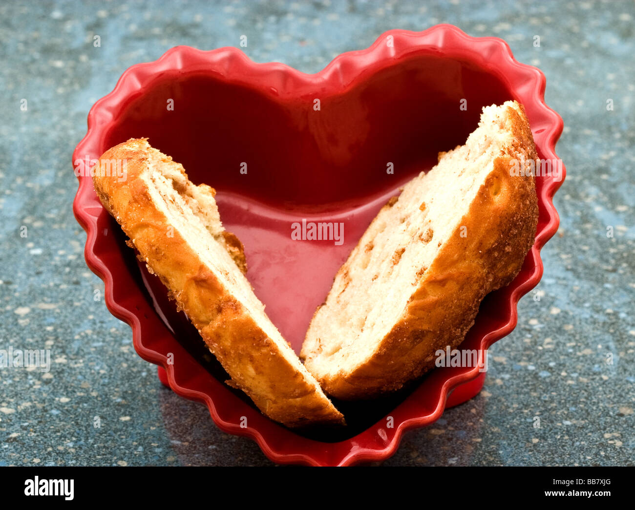 Cinnamon bagel split in half in a red heart shaped dish Stock Photo