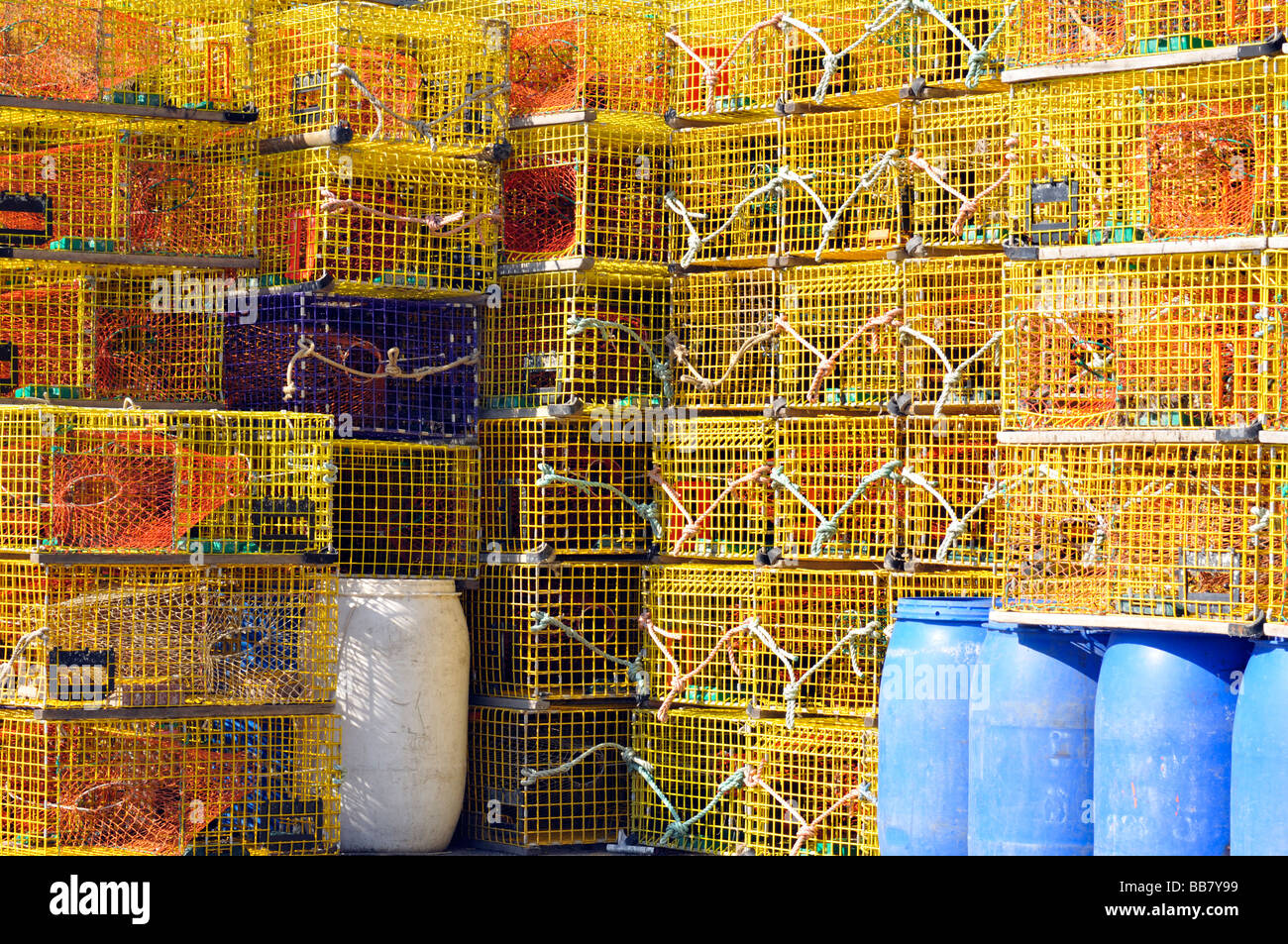 Large stacks of new yellow lobster traps with one blue trap ready for fishing in Newport Harbor Rhode Island Stock Photo
