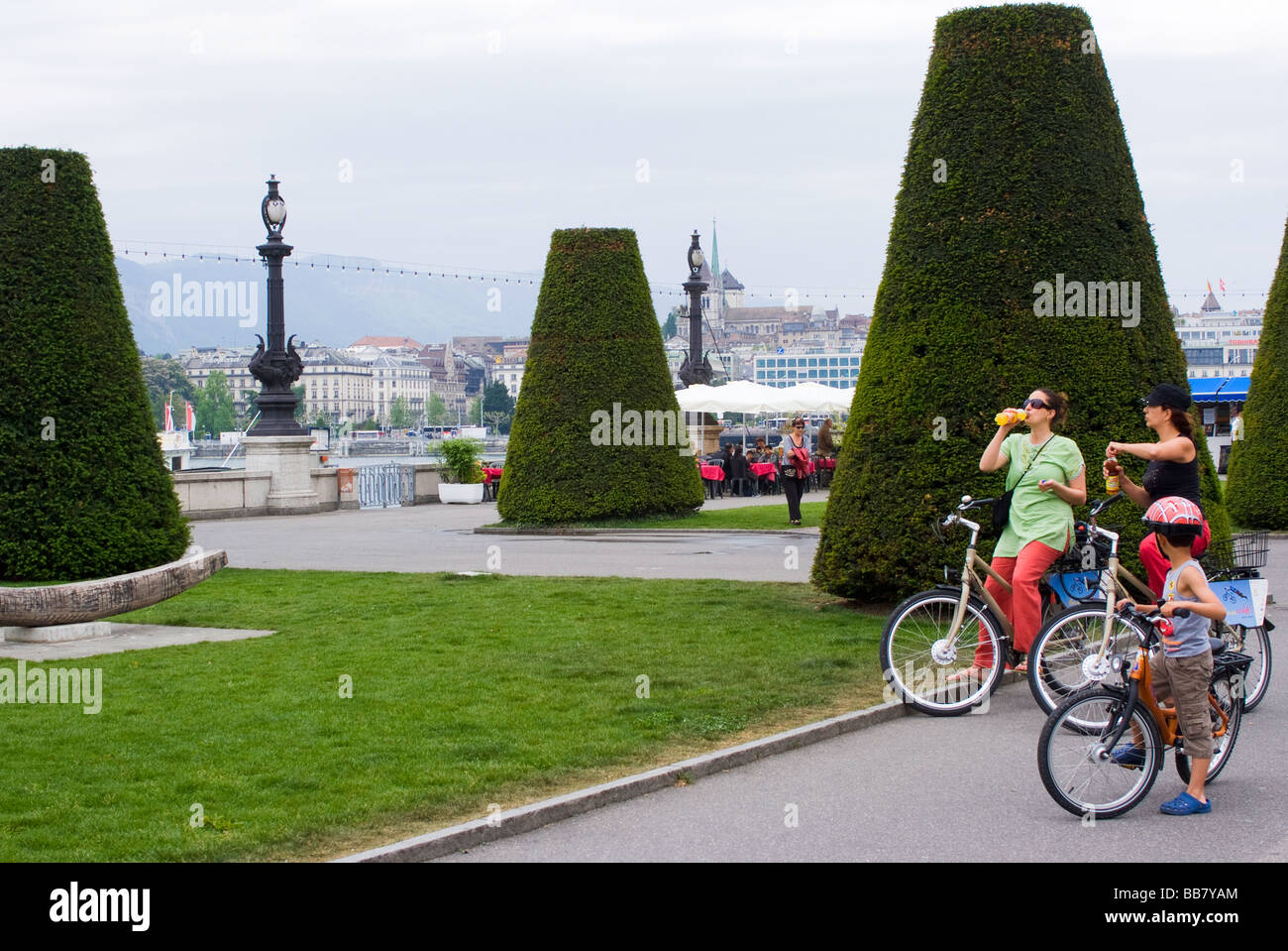 Children on Bicycles In Quai du Mont-Blanc with Shaped Trees Lake Geneva Geneve Switzerland Suisse Stock Photo