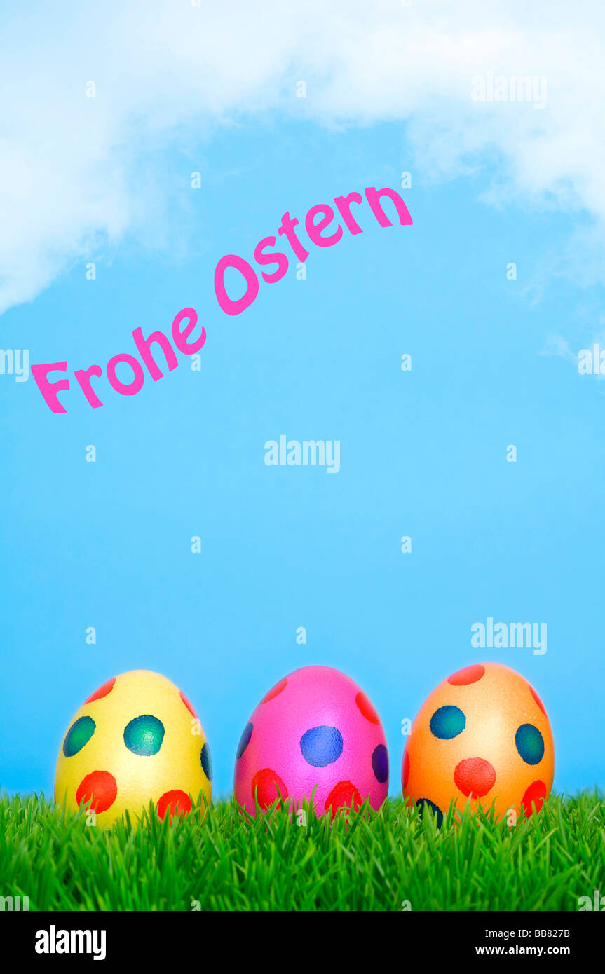 Colourful Easter eggs on grass with blue sky, Frohe Ostern, happy Easter in writing Stock Photo