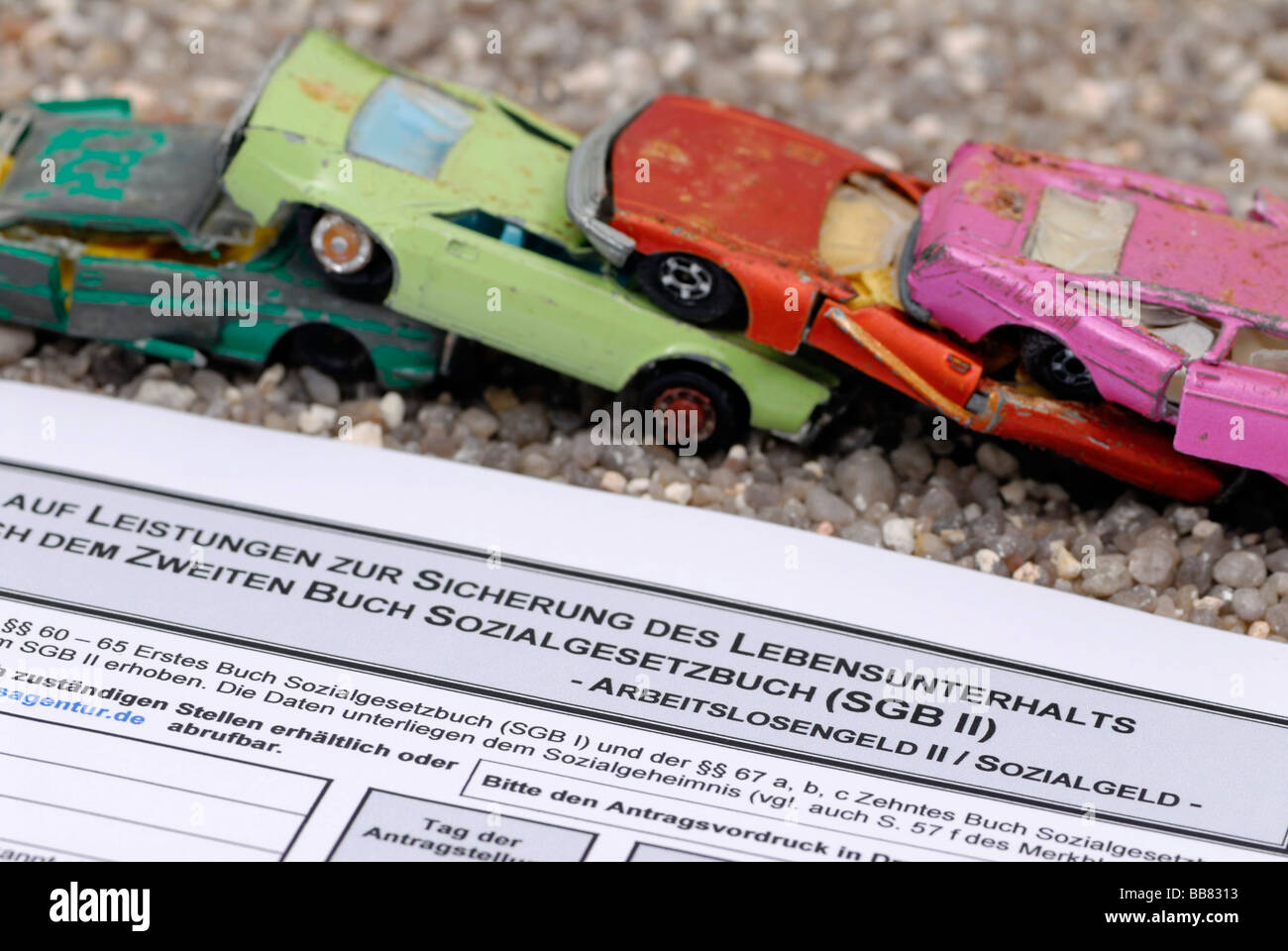 Broken miniature cars stacked on an unemployment benefit form, symbolic picture for scrapping premium for Hartz-IV recipients Stock Photo