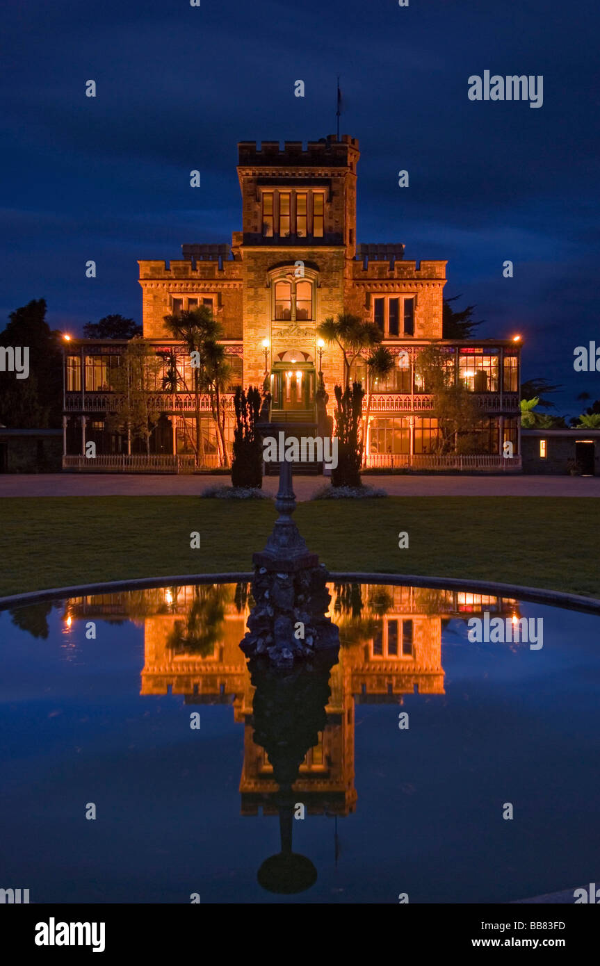Larnach Castle on the Otago Peninsula and its reflexion in the pond of a fountain illuminated by floodlight, New Zealand Stock Photo