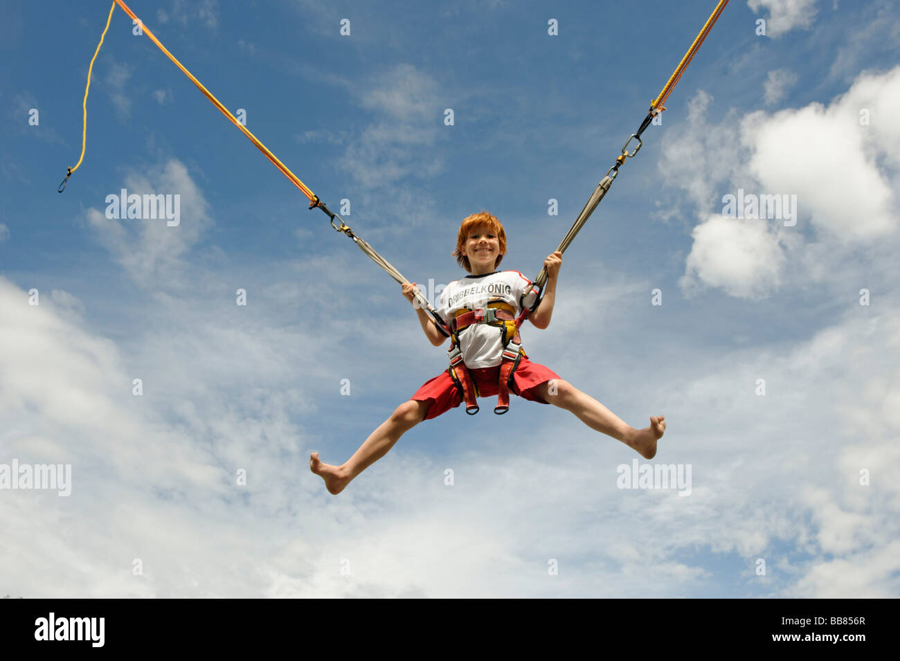 Young boy jumping on a bungee trampoline and flying in the air Stock