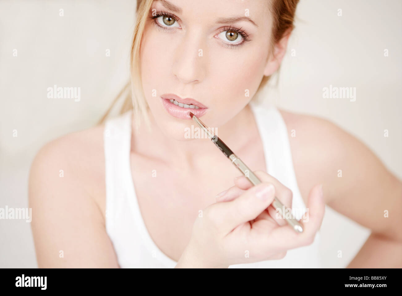 Portait of young beauty woman applying lip gloss on lips Stock Photo
