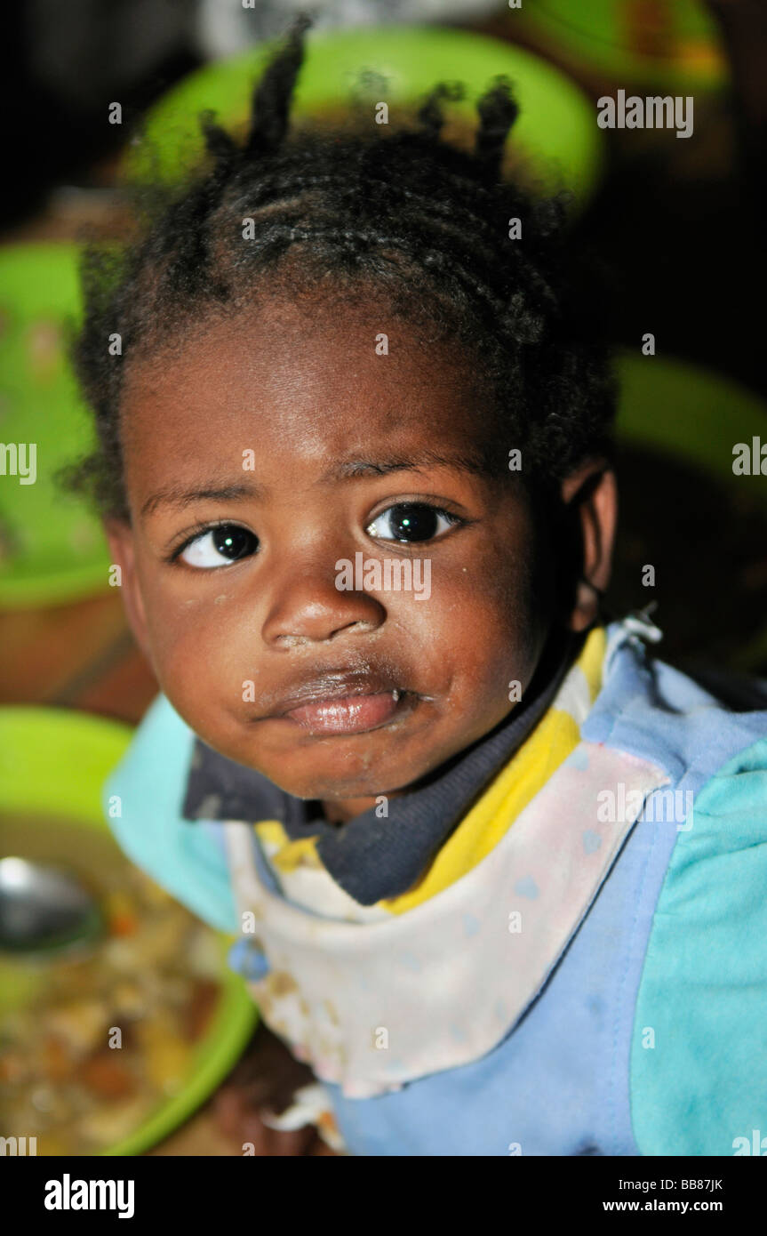 Small, dark skinned, cross-eyed girl in a soup kitchen, slums of Alto de Cazuca, Soacha, Bogotá, Columbia Stock Photo