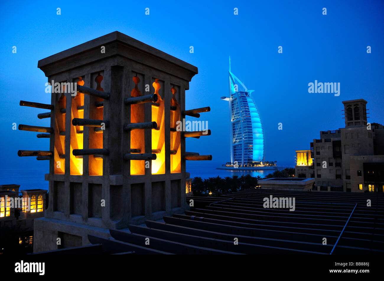 Stylized wind tower of the Madinat Jumeirah resort in front of the illuminated facade of the seven-star hotel Burj al Arab, Ara Stock Photo