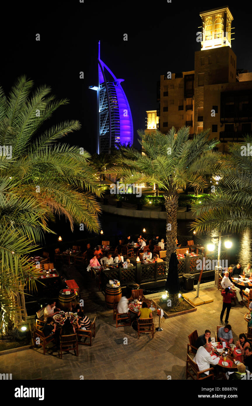 Open-air restaurant at the Madinat Jumeirah resort in front of the illuminated facade of the seven-star hotel Burj al Arab, Ara Stock Photo