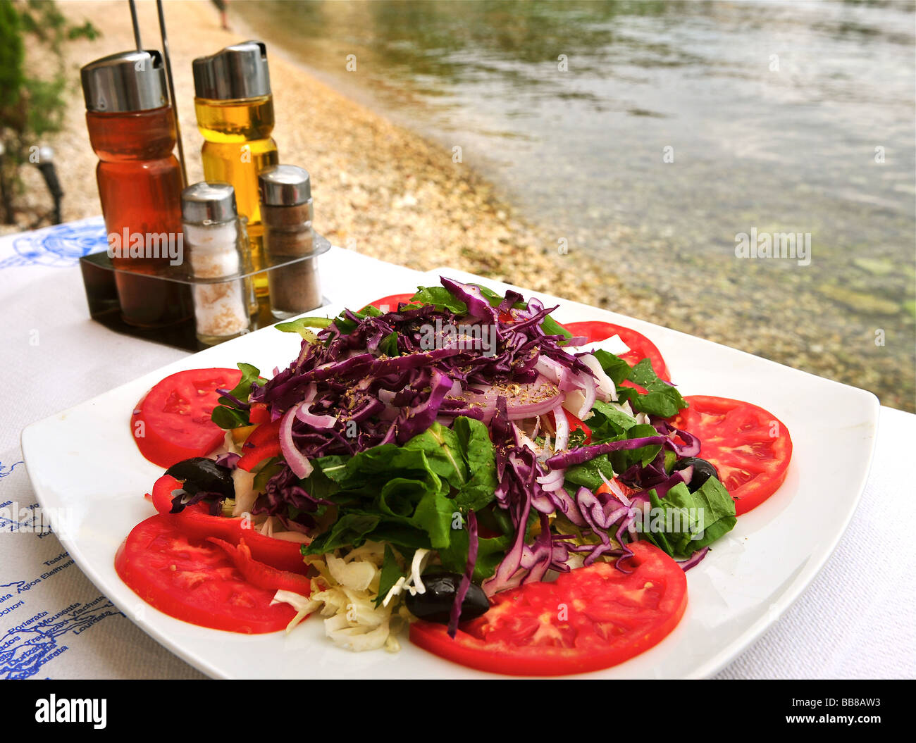 Tomato salad served outside at a table beside the sea. Stock Photo