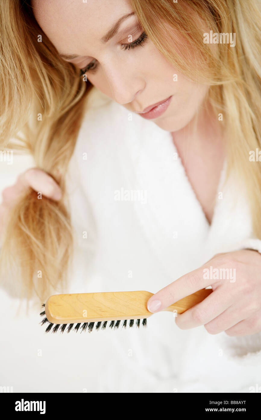 Portrait of young woman in dressing gown brushing her hair Stock Photo