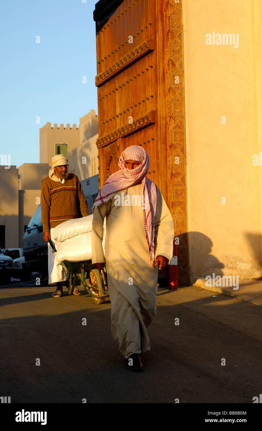 Two Arabian dressed Omani men passing through the gate to Souq, Nizwa, Sultanate of Oman Stock Photo