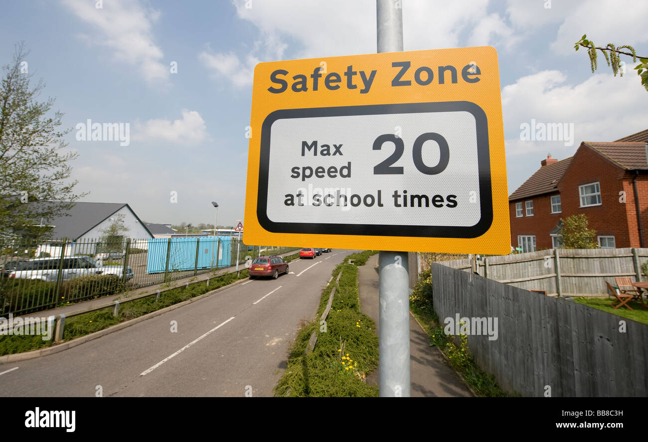 Yellow road sign showing a speed limit of 20 miles per hour at school times in a safety zone outside a school Stock Photo