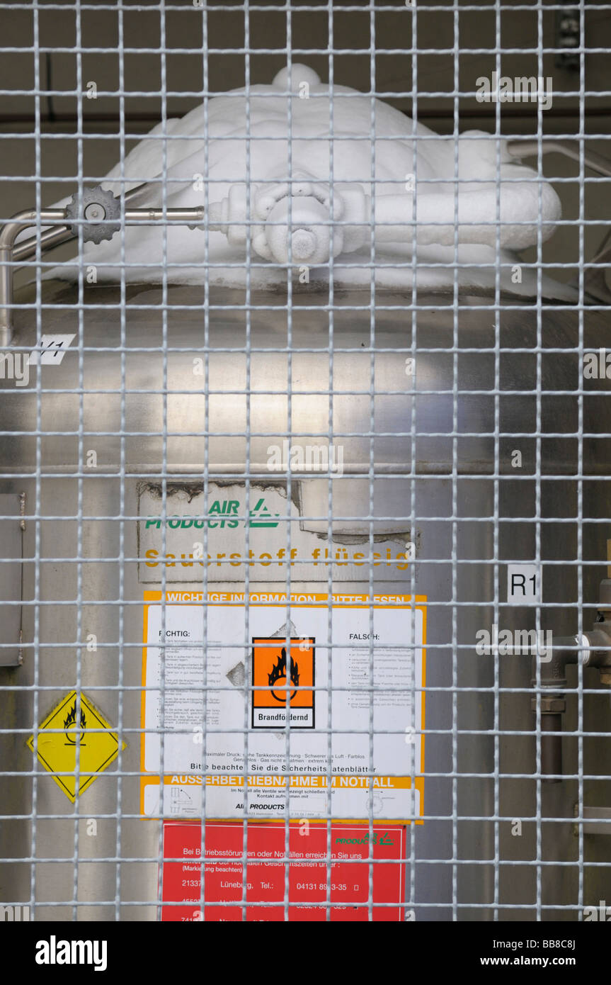 Tank of liquid oxygen behind a protective wire grid, top fittings are covered with ice, hazard symbol for oxidating substances Stock Photo