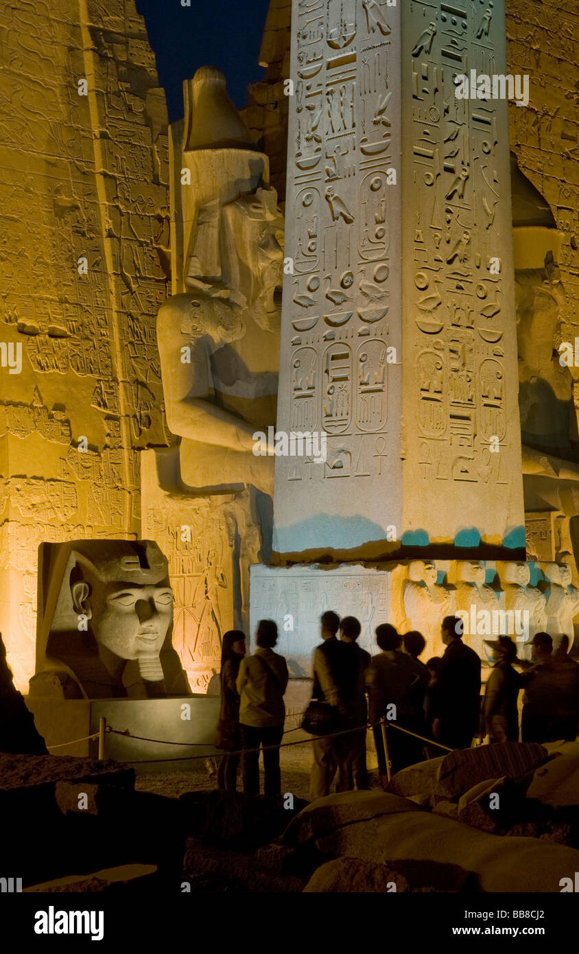 Pylon with seated figures and obelisk of Ramesses II illuminated in the evening, head of Ramesses II at the front, Luxor Temple Stock Photo