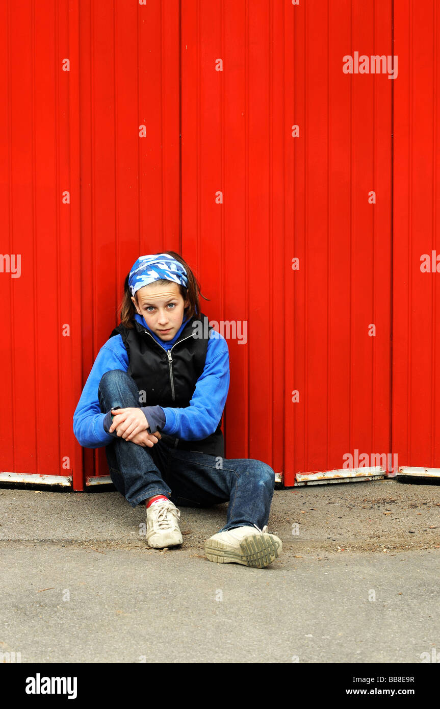 portrait of modern child leaning against red wall Stock Photo
