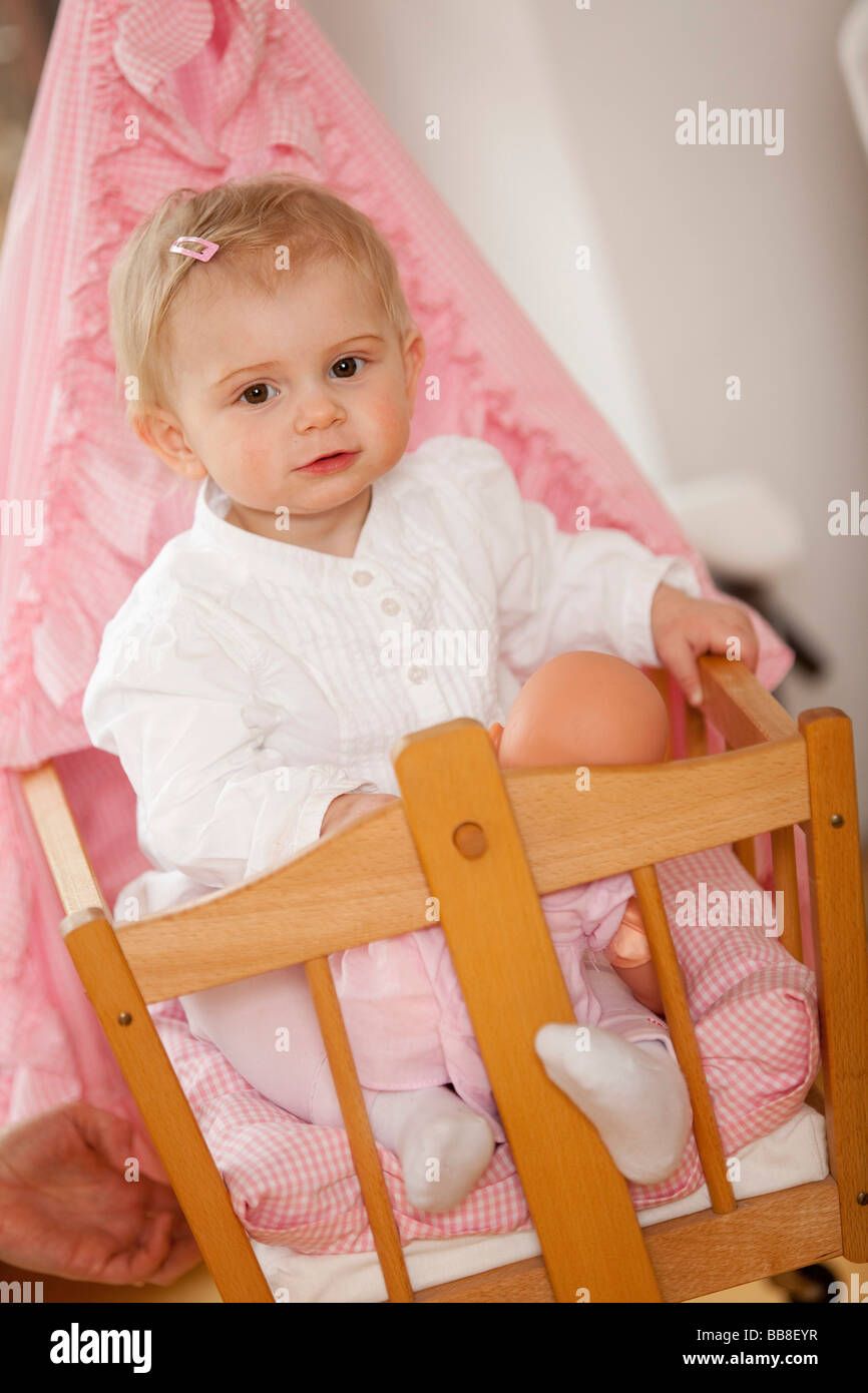 Young girl, 1 year old, sitting in her doll's pram Stock Photo