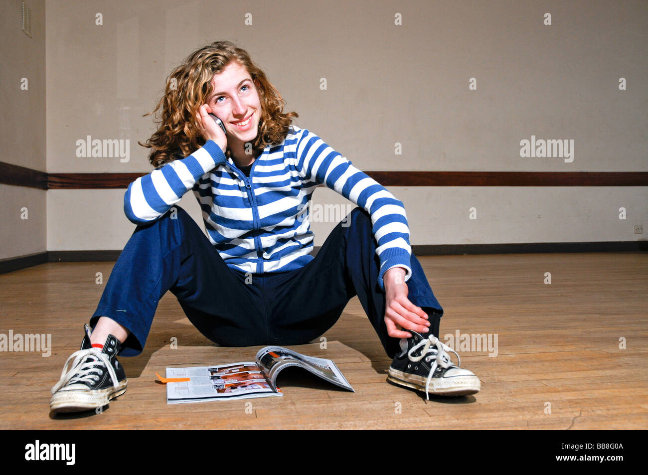 portrait of teenage girl reading magazine and talking on cell phone Stock Photo