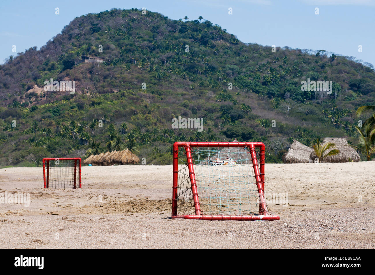 Red soccer goals on sandy beach in Nayarit, Mexico with hillside behind. Stock Photo