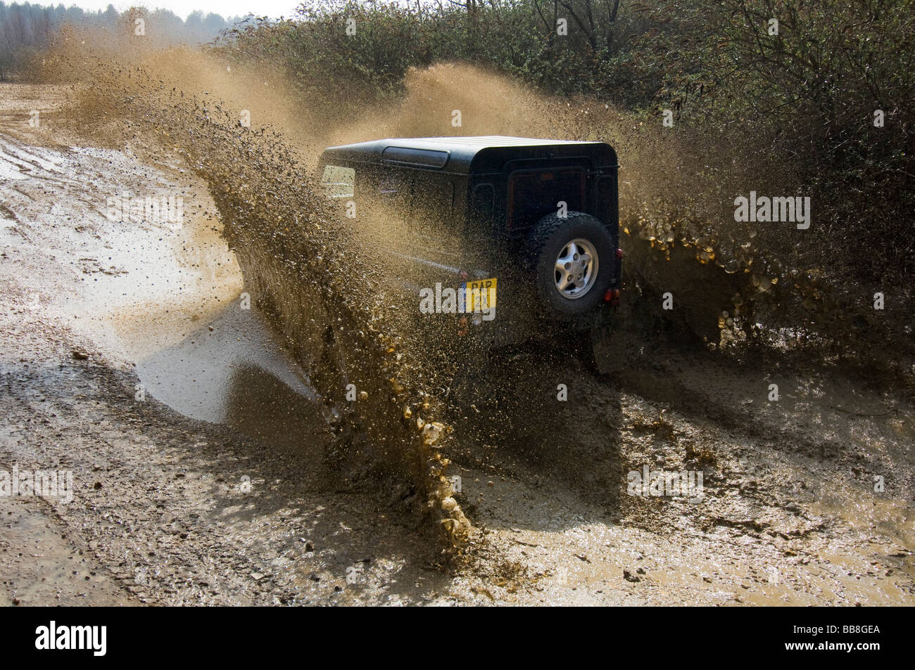 A Landrover Defender driving along a muddy track on an off road exercise Stock Photo