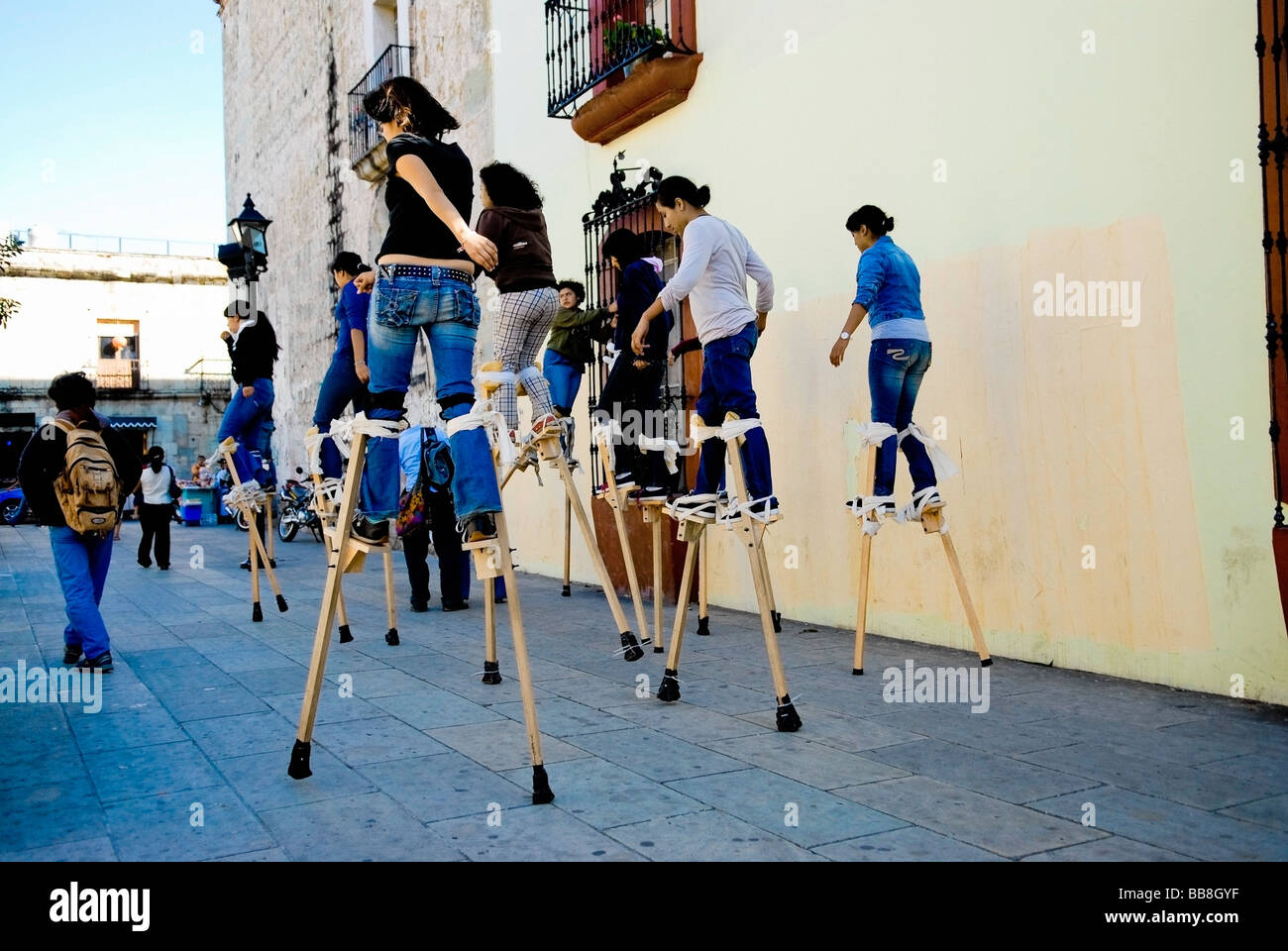 Teenage girls walking on stilts on street; Mexico Stock Photo