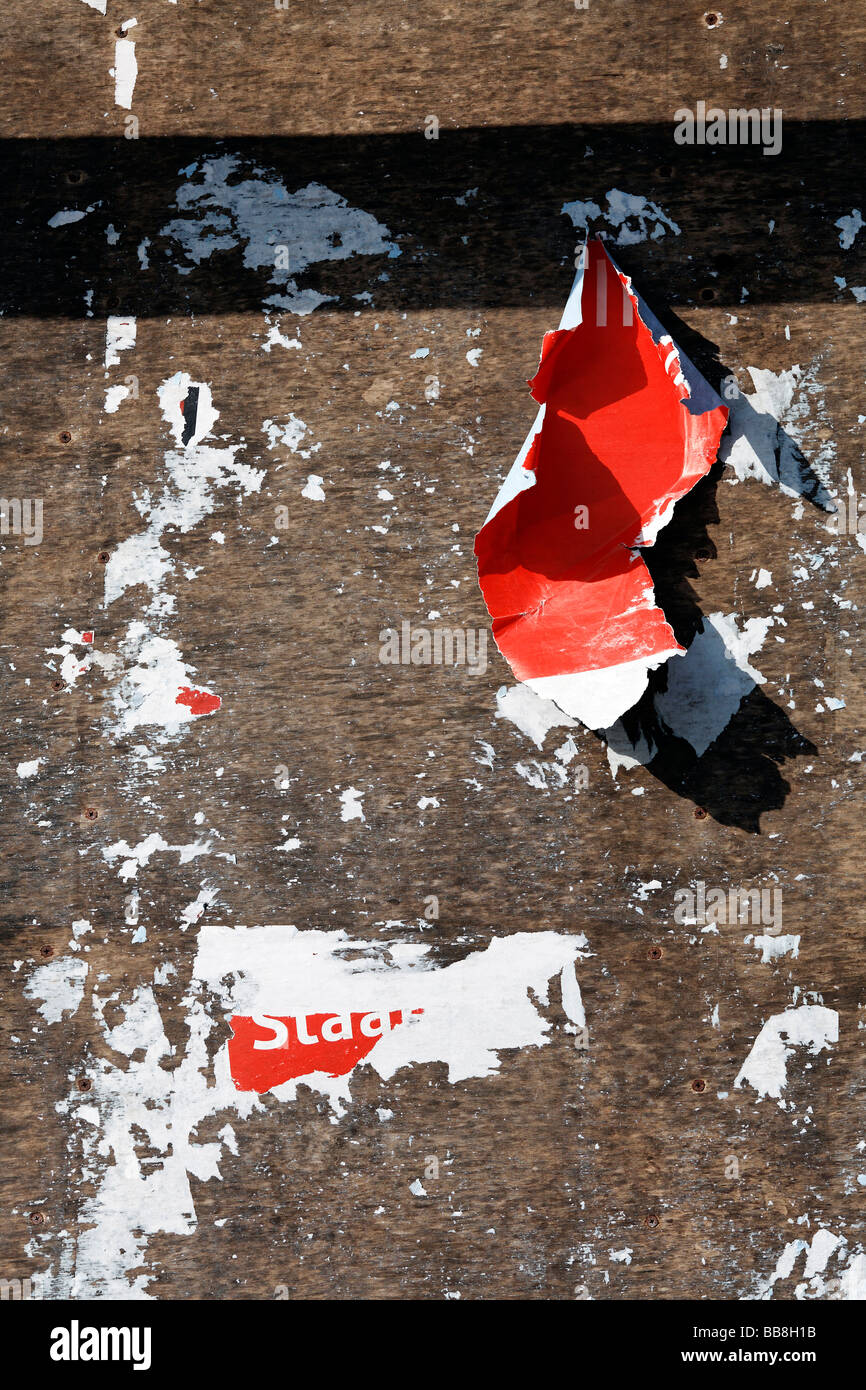 Billboard with torn poster bits, red paper. Stock Photo
