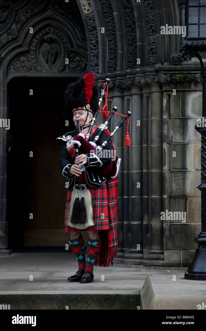 Male piper playing scottish bagpipes outside 'St Giles' Church, Edinburgh, Scotland, UK, Europe Stock Photo