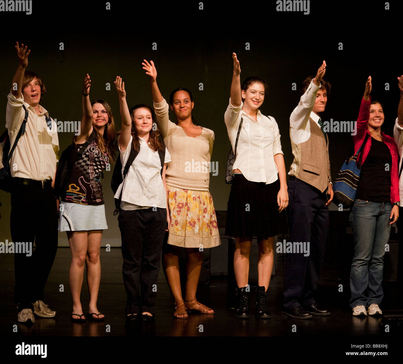 students waving to the audience at curtain of high school theatre