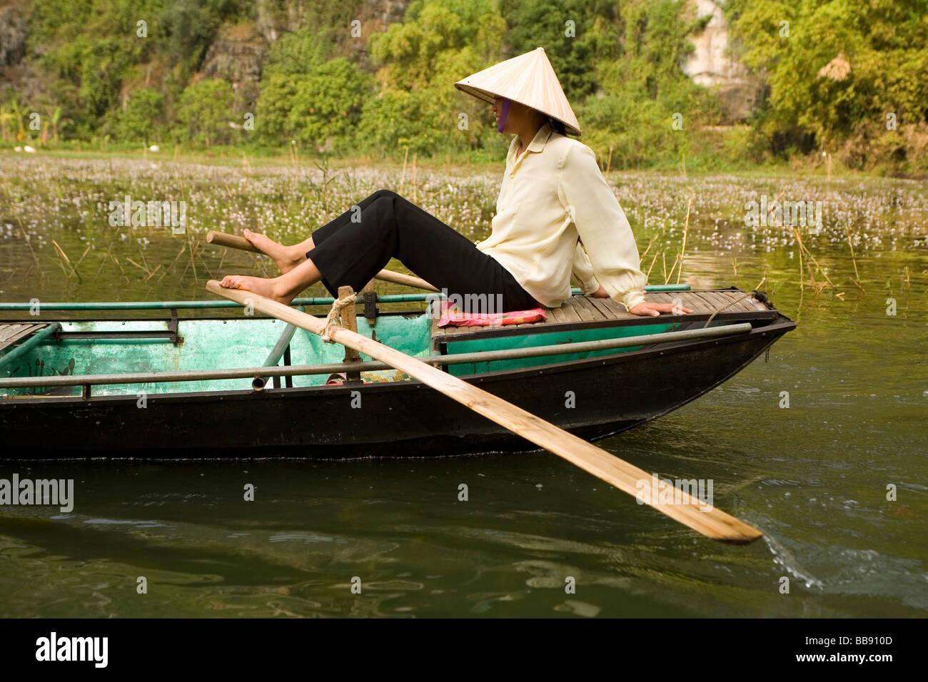 Woman rowing her boat with her feet on the Ngo Dong River at Tam Coc near  Ninh Binh Vietnam Stock Photo
