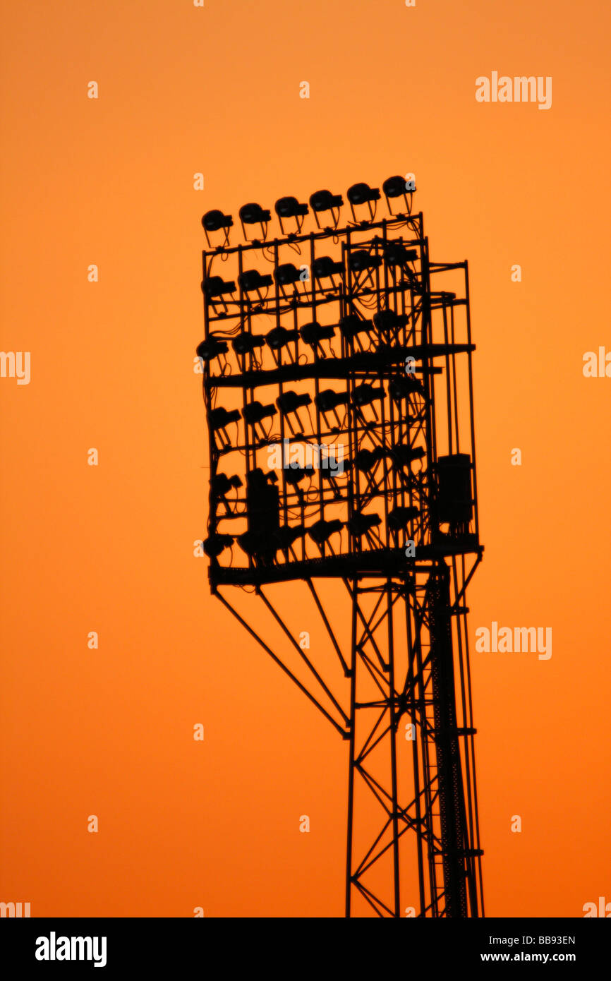 Floodlights at a Sports Stadium Silhouetted against a Sunrise or Sunset Sky Stock Photo