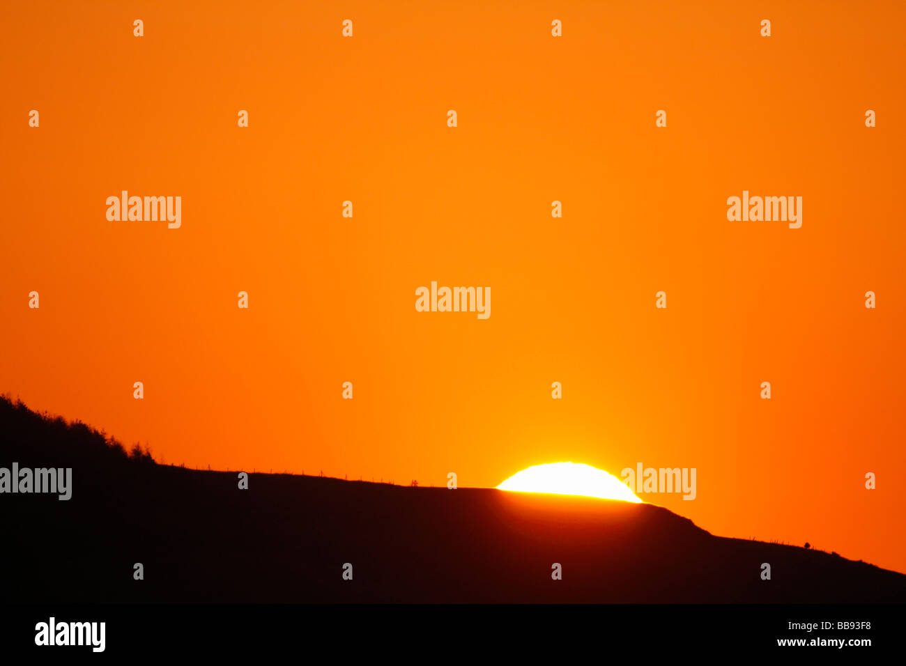 Sun Rising Over a Hillside Stock Photo