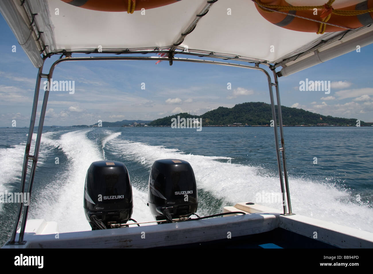 A view of the back of a speed boat wake with the island of Borneo