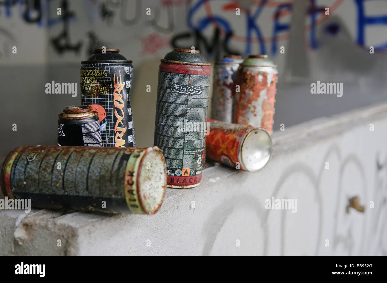 Paint cans/aerosols on a wall, grafitti in background Stock Photo