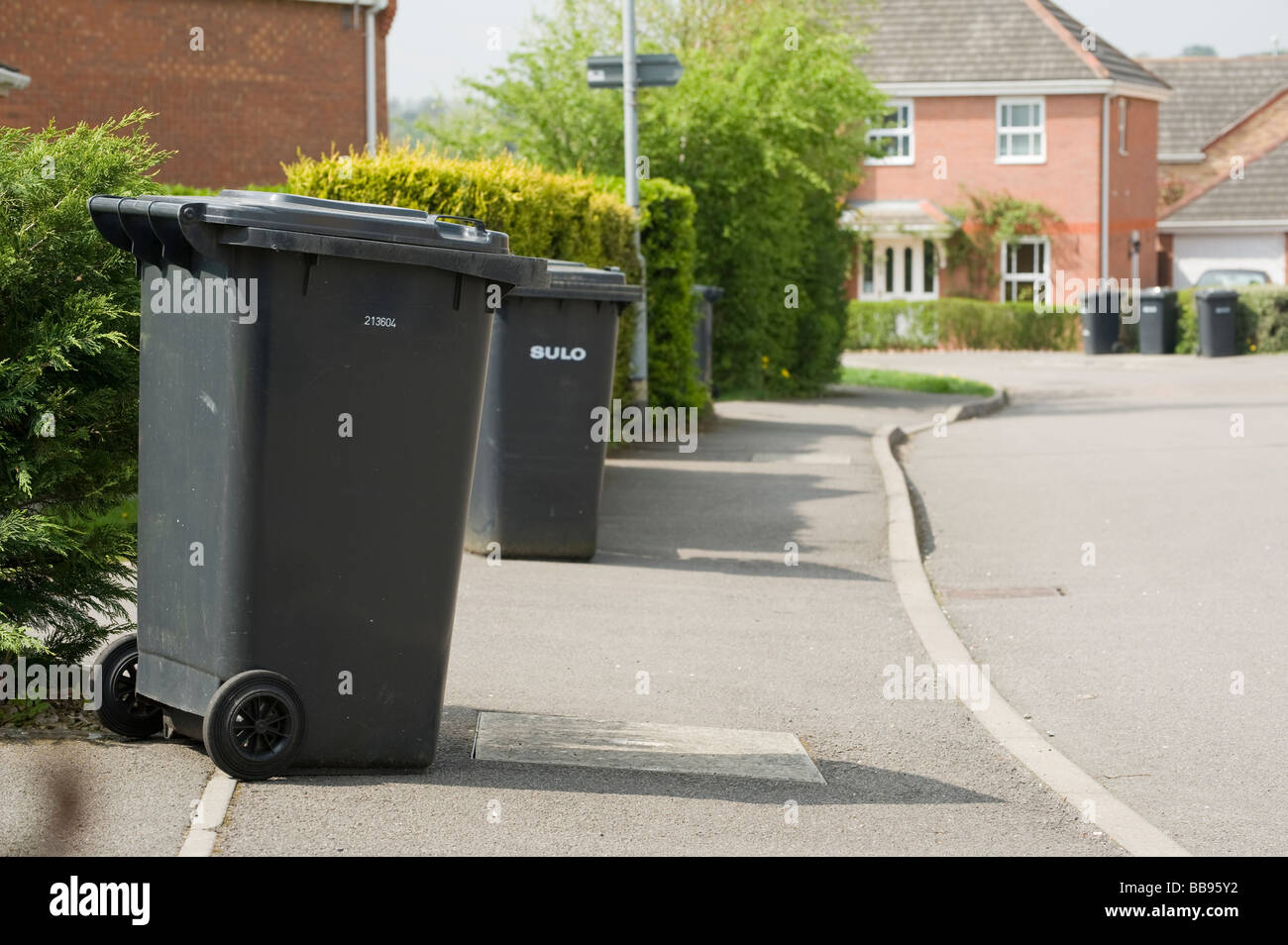 Black rubbish wheelie bins waiting to be collected on a street in England Stock Photo