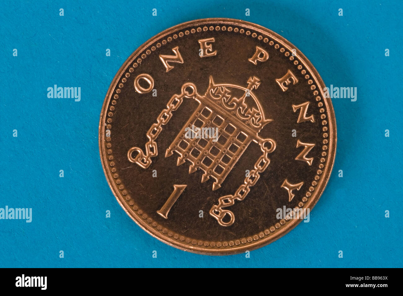 One shiny new one penny coin against a blue background Stock Photo