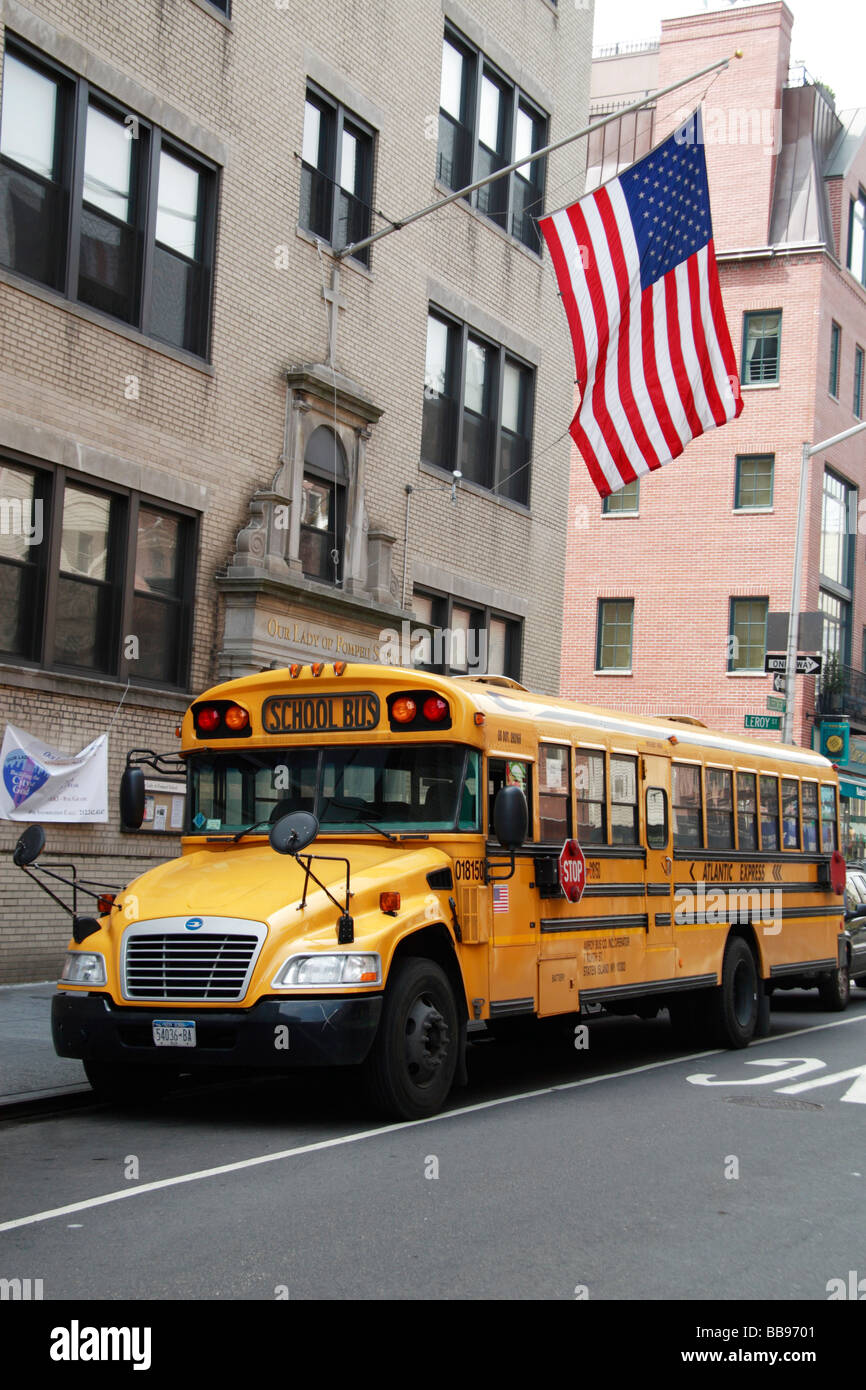 A traditional American yellow school bus with the star spangled banner flying on the building behind. Stock Photo
