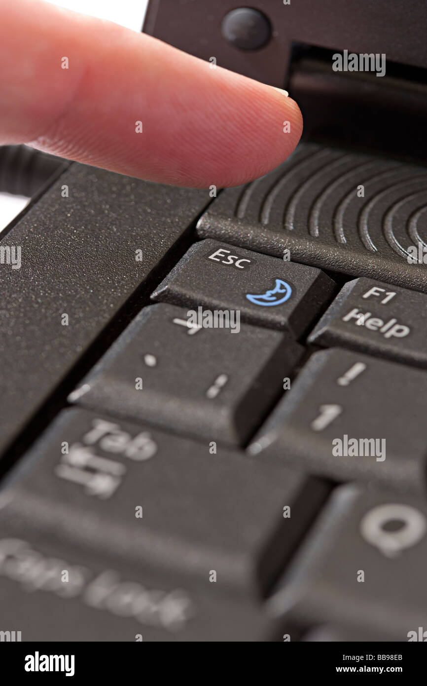 finger over the escape key of a laptop Stock Photo