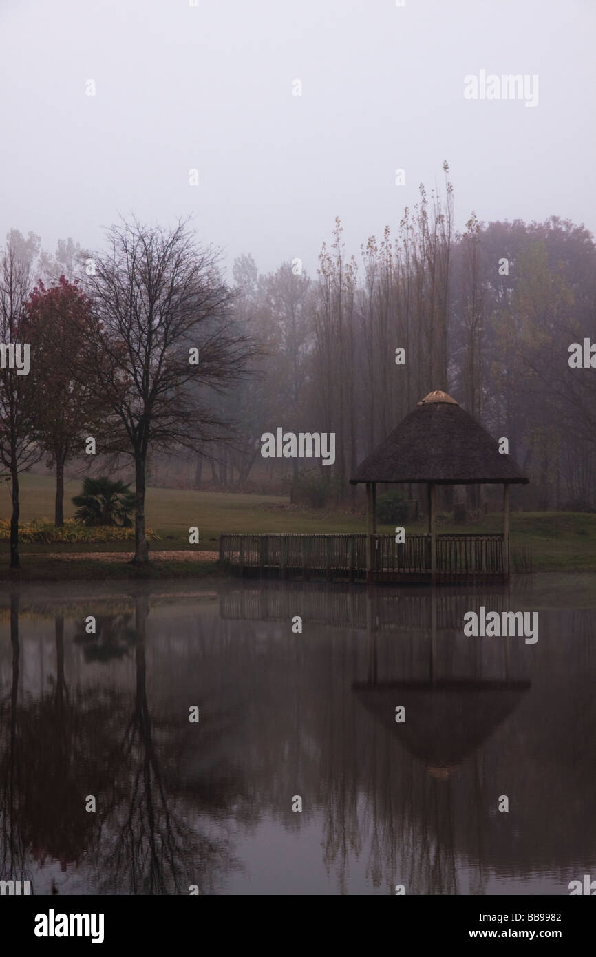 Reflection of thatched gazebo in the mist Stock Photo